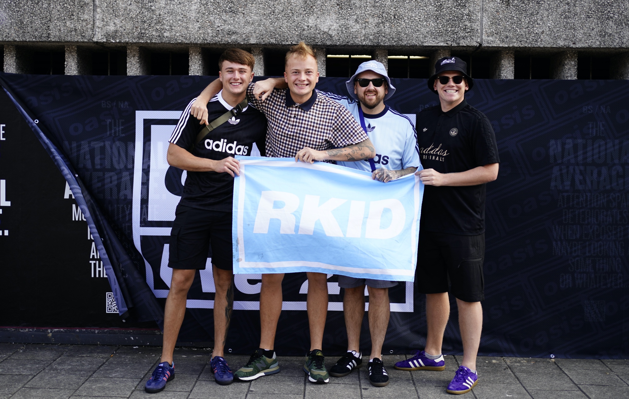 Oasis fans pose for pictures with an "Rkid" banner outside the Principality Stadium, Cardiff, photo by Jordan Pettitt/PA Images/Getty