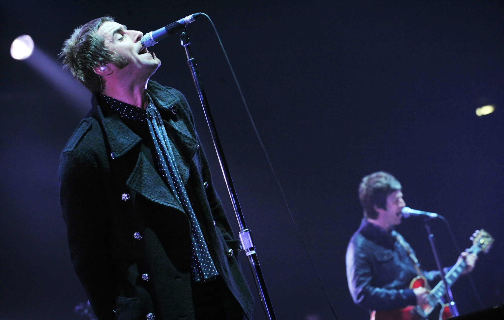 Liam Gallagher and Noel Gallagher performing live with Oasis