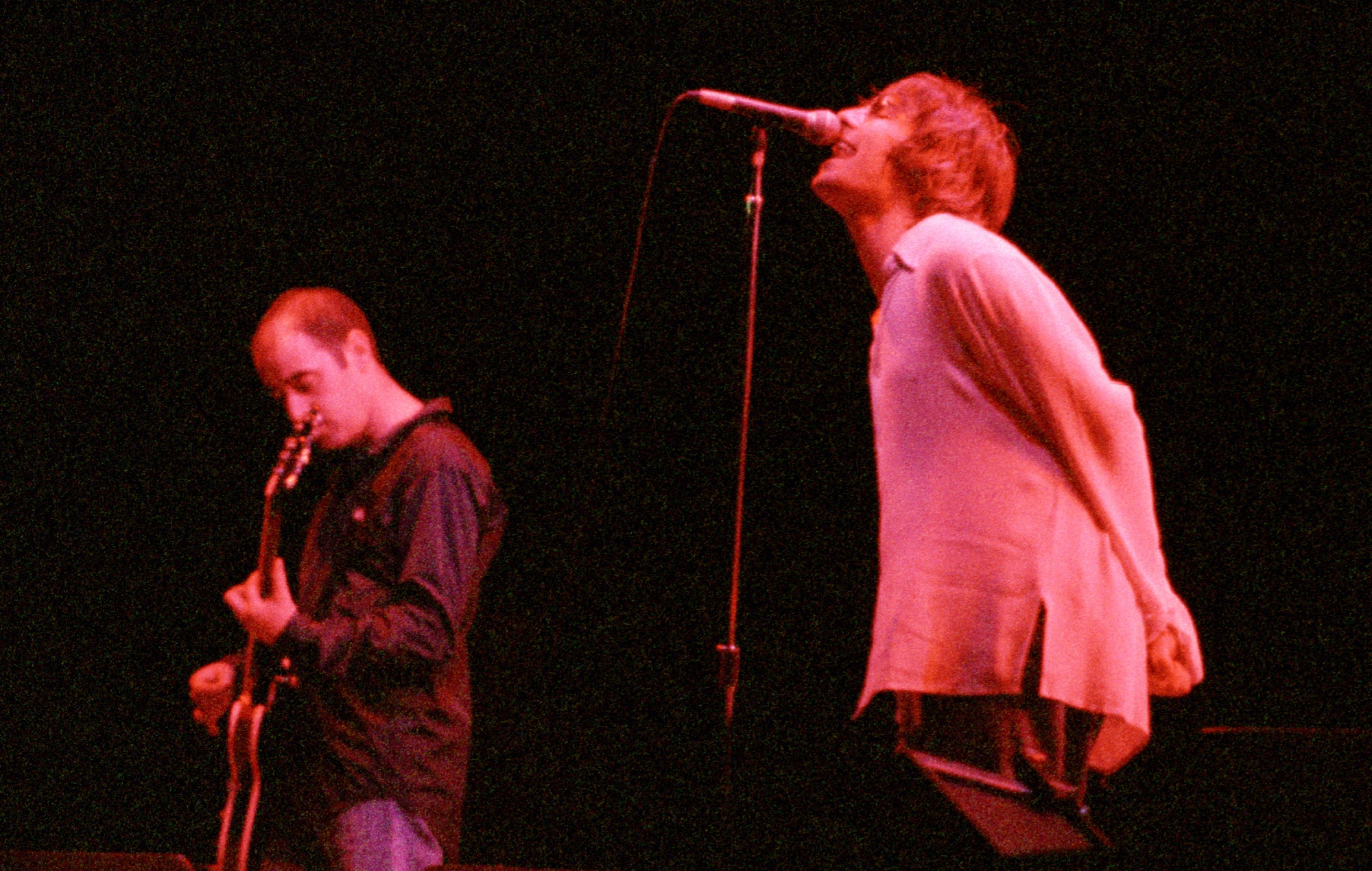 Paul 'Bonehead' Arthurs and Liam Gallagher performing live on stage with Oasis in 1996