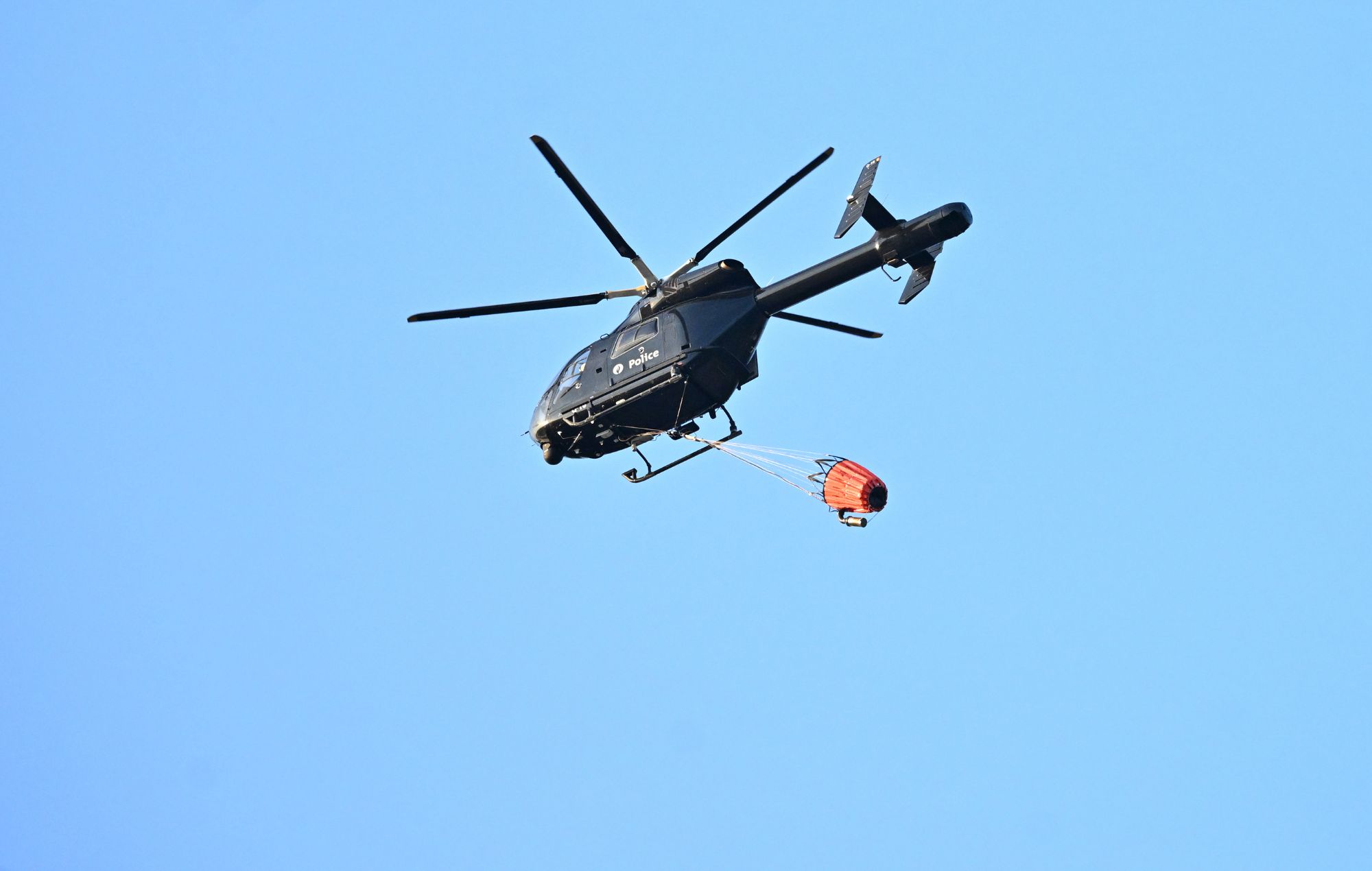 A police helicopter carries water to help extinguish the flames after a fire broke out at the festival site of the Tomorrowland