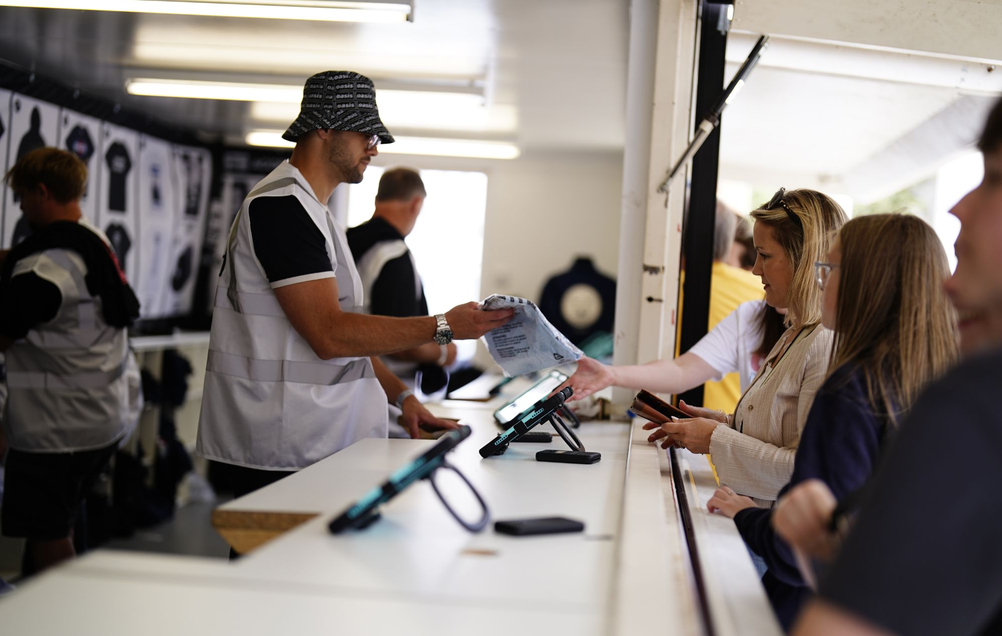 Oasis fans purchase merchandise from the official stand outside the Principality Stadium, Cardiff