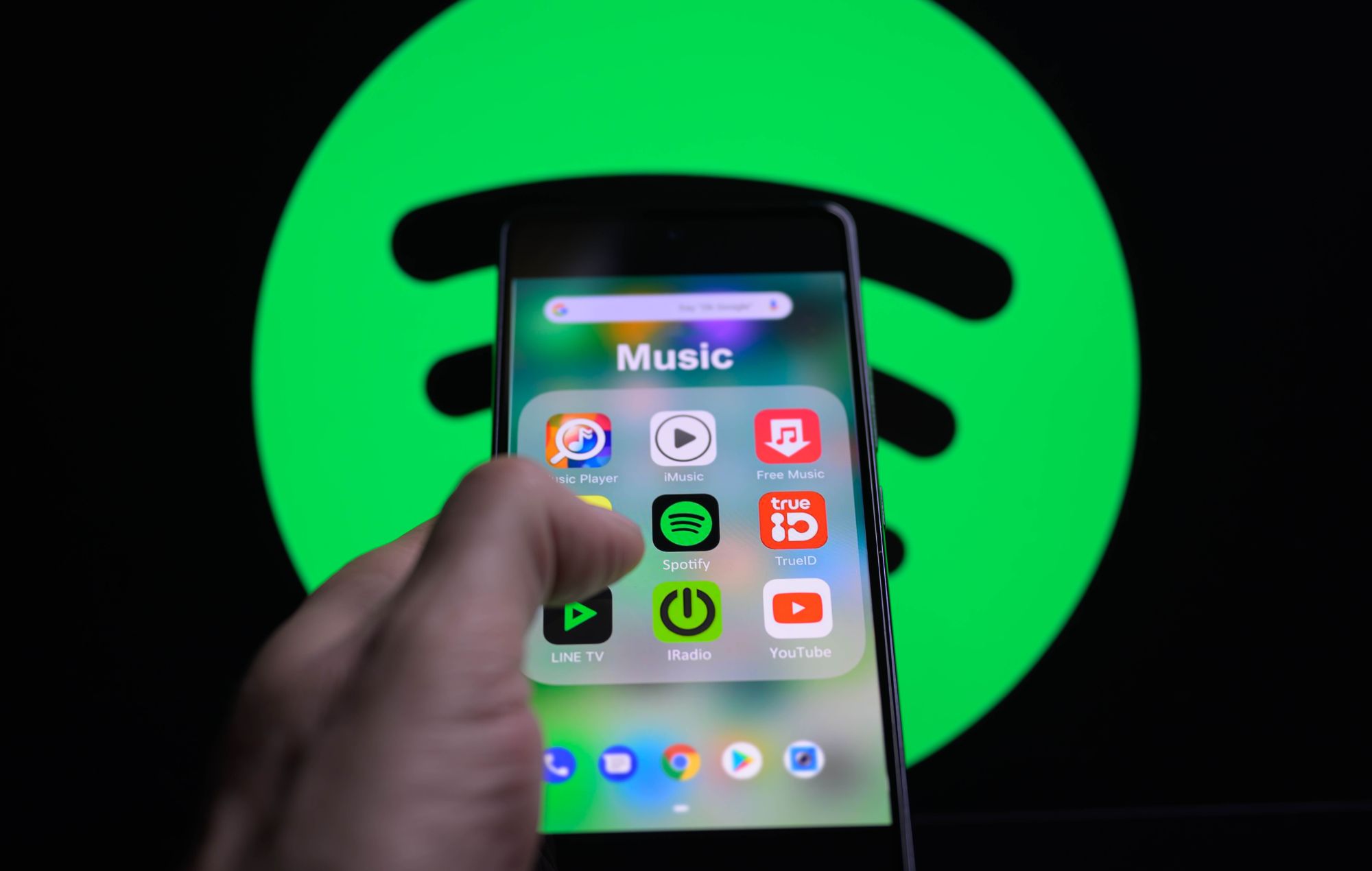 Spotify app icon is being displayed on a smartphone with Spotify visible in the background