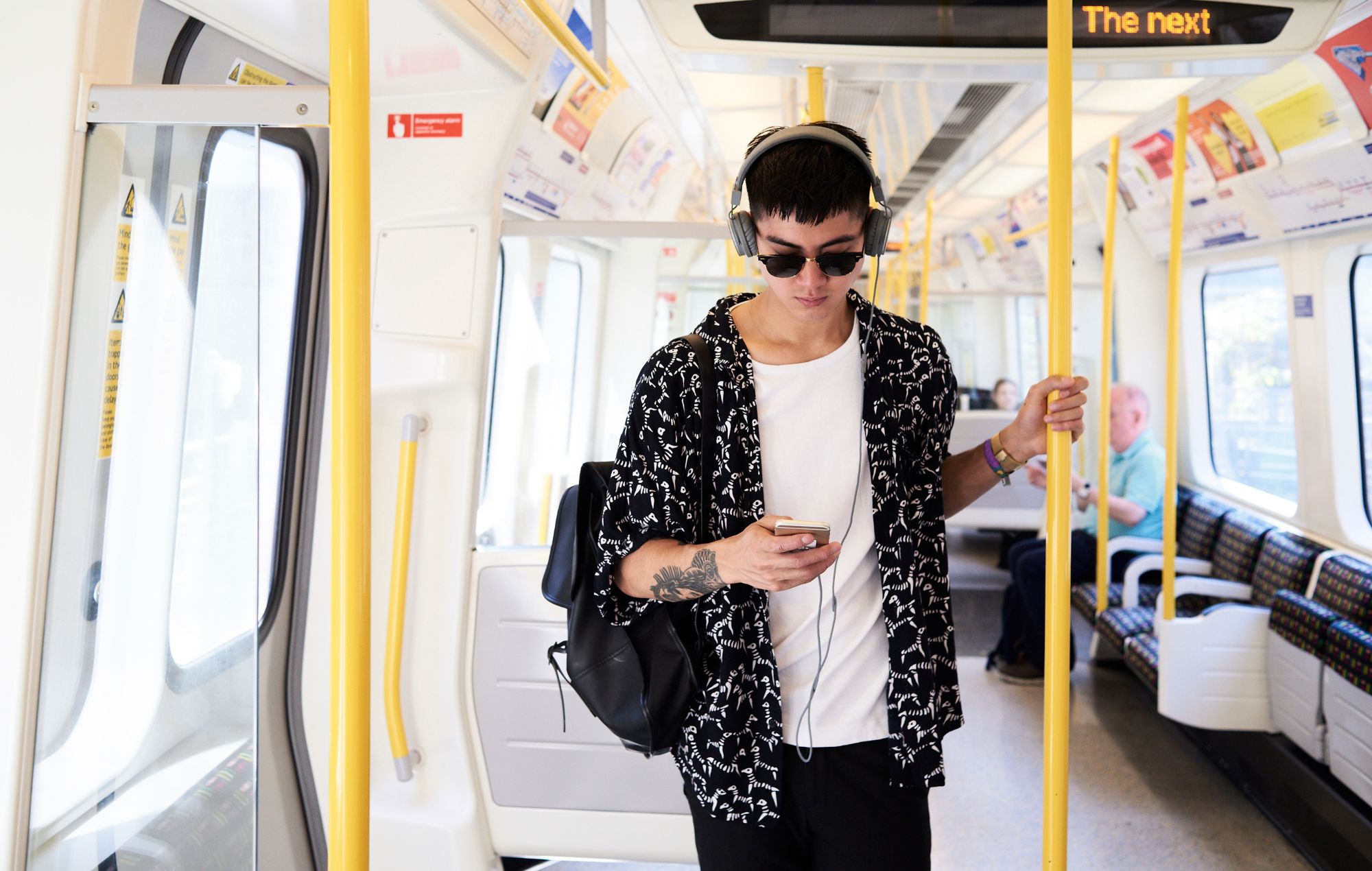 Young man listening music with headphones inside train, UK